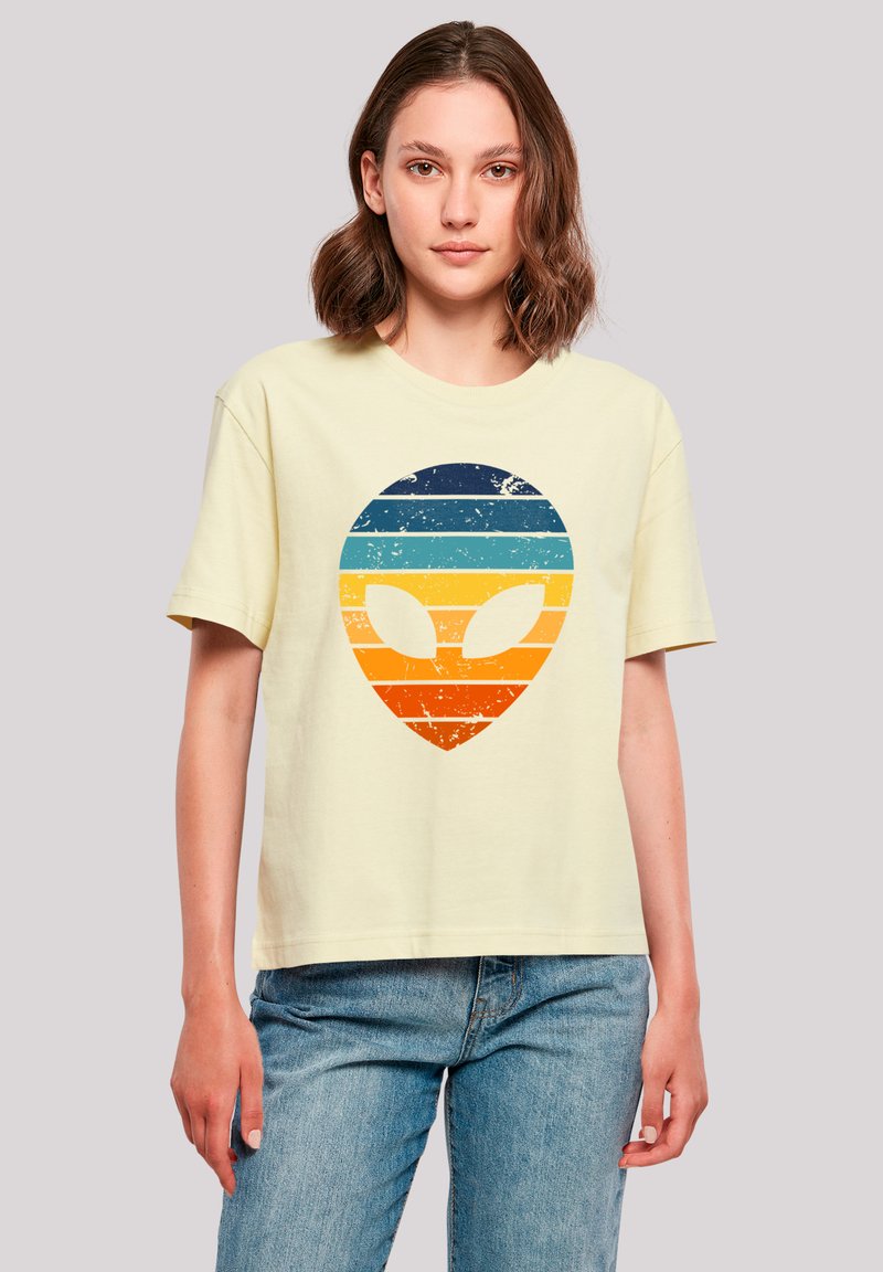 Light yellow cotton t-shirt featuring a distressed alien face graphic, colored in blue, teal, orange, and yellow horizontal stripes.