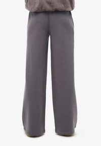 Grijze sweatpants met wijde pijpen, gemaakt van zachte stof, met een elastische tailleband, zijzakken en een gladde textuur zonder zichtbare patronen.