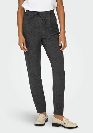 Op maat gemaakte grijze broeken met een gestructureerde stof, een tailleband met trekkoord, taps toelopende pijpen en zijzakken, gecombineerd met crèmekleurige loafers.
