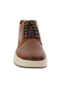 Zapato de cuero marrón con atado negro, punta redondeada y suela de goma blanca texturizada. Presenta costuras laterales y un detalle mínimo.