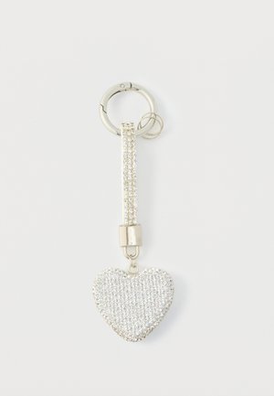 Chaveiro prateado com um pendente em forma de coração, coberto por strass transparentes, ligado a um anel prateado brilhante e a uma correia texturizada.