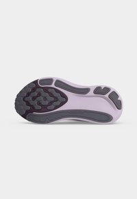 Sohle eines hellvioletten Sneakers mit dunkelgrauen Gummi-Traktionsmustern und strukturierten Griffbereichen auf einfarbigem Hintergrund.