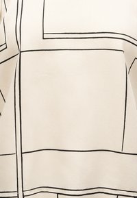 Υφασμα σε κρεμ απόχρωση με μαύρο γεωμετρικό πλέγμα που εμφανίζει μεγάλα τετράγωνα και ορθογώνια με ορατές ραφές.