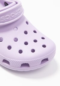 Cruză purpurie cu un design ușor, texturat, având multiple orificii de ventilație și o curea pentru o potrivire sigură.