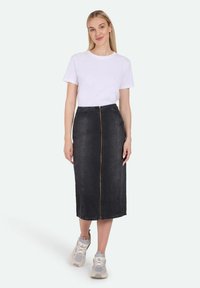Sort denim midi-nederdel med lynlås foran, suppleret med en simpel hvid t-shirt og lyse sneakers til en afslappet stil.