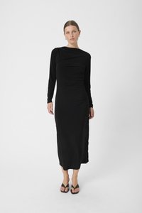 Musthave mustriline rikkusmustalne kleit on valmistatud siledast kangast. Sellel on rippuv kaelus ja põlvepikkus. Kandmiseks on kombineeritud mustade plätudega.