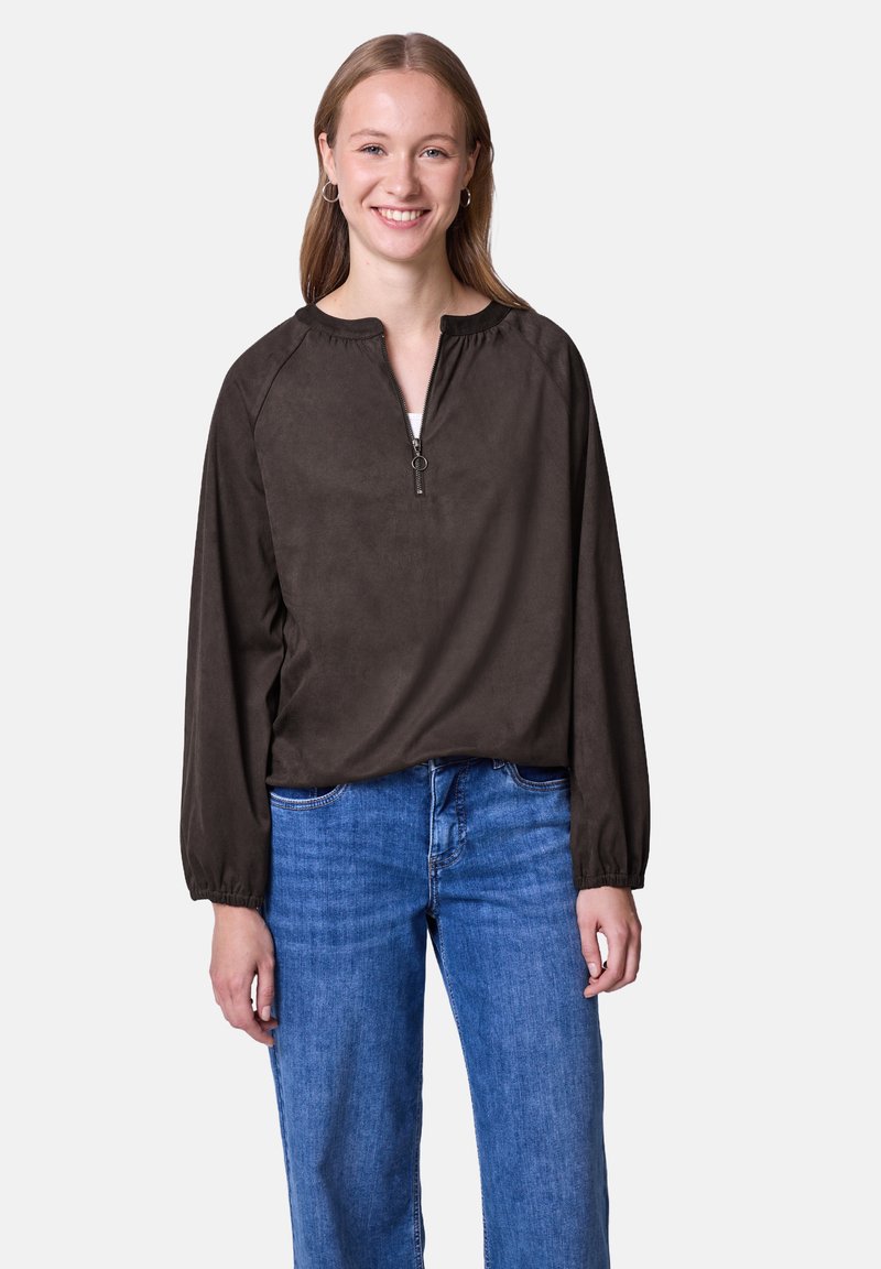Brun lynlås langærmet top med rund hals; blødt stof, let løs pasform, elastiske manchetter. Sammen med blå denim jeans.