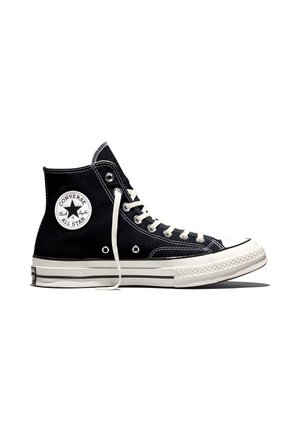 Scarpa nera alta Converse All Star Chuck Taylor con lacci bianchi, suola in gomma e toppa con logo sulla caviglia.