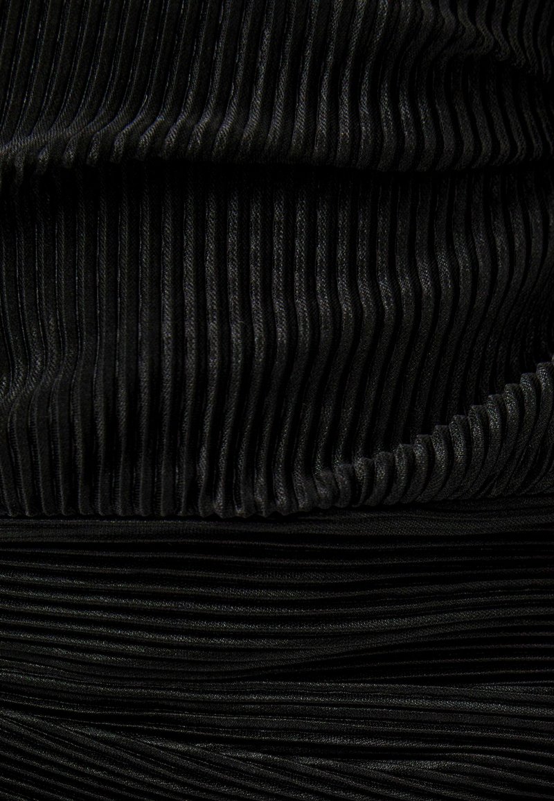 Černá skládací tkanina s vertikálními pruhy, která ukazuje texturovaný povrch. Materiál je jemný s jemným leskem a rovnoměrnými, konzistentními sklady.