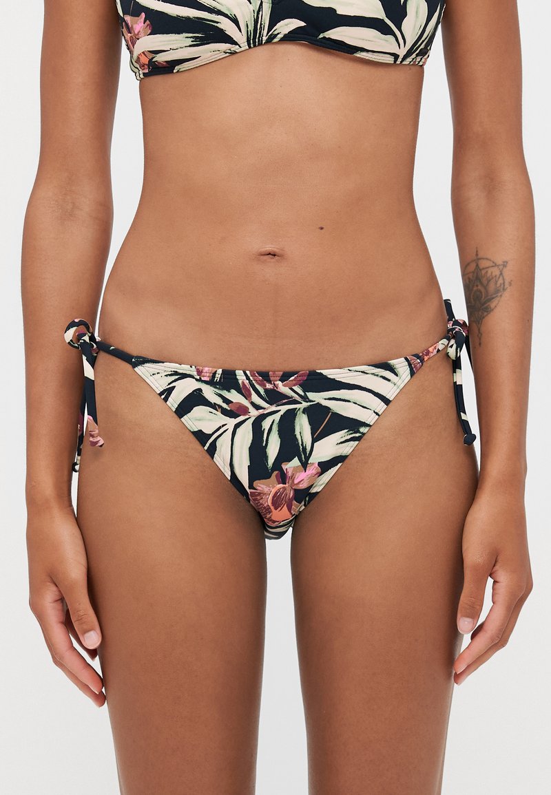 Virágmintás bikini alsó sötétkék háttérrel, oldalsó megkötőkkel, minimális takarással, trópusi levelek és virágok keverékével.