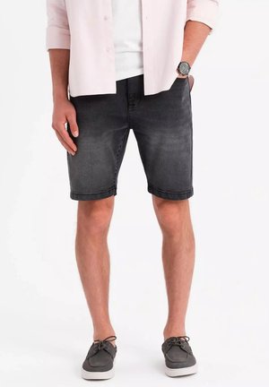 Sorte denimshorts med slim fit, opsmøget kant og let falmning. Kombination med en lys skjorte og casual grå bådsko.