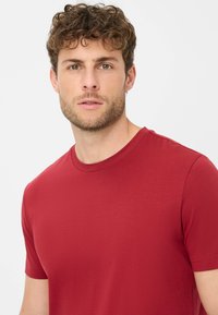 Rotes Kurzarm-T-Shirt aus glattem Stoff mit Rundhalsausschnitt. Einfach, einfarbig ohne sichtbare Muster oder Akzente.