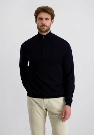 Marinekleurige zip-up trui met hoge kraag, lange mouwen en ribgebreide manchetten. Gepaard met beige corduroy broek, met een gestructureerde stof.