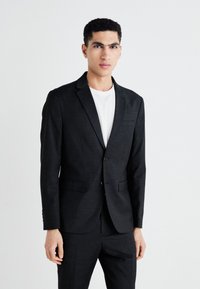 Crni odijelo s jaknom prilagođenog kroja, sa slim fit krojem, jednim gumbom zatvaranja, reverima na izrez i strukturiranom siluetom. Glatka tekstura.