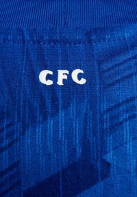 Tissu bleu avec des motifs de couture verticaux et les lettres blanches "CFC" imprimées au centre.