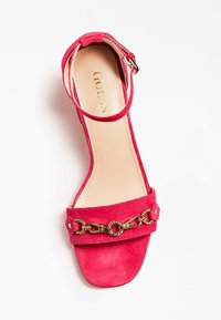 Sandal in camoscio rosa con una cinghia e un accento di catena dorata, dotata di punta aperta e di una cinghia alla caviglia regolabile per una vestibilità sicura.