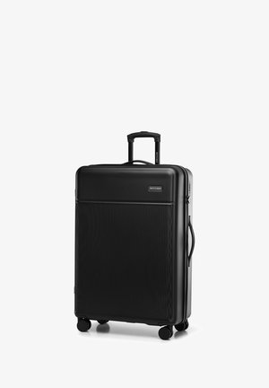 Zwarte harde koffer met verticale geribbelde textuur, uitschuifbare handgreep en vier wielen voor mobiliteit. Voorzien van zijhandgreep om te tillen.