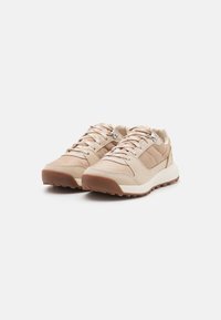 Beige sportcipők sima és texturált anyagok keverékéből, párnázott bokarész és mintás gumitalp a tapadás érdekében.