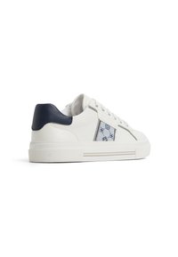 Zapatilla blanca con acabado texturizado, acento de cuero azul en el talón y panel lateral decorativo que presenta patrones y costuras azules.