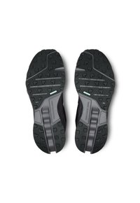 Semelles de chaussures de sport noires avec un caoutchouc texturé pour une meilleure adhérence, présentant des accents moulés et une section centrale lisse. Conçues pour la performance.