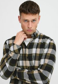 Koszula w kratę w odcieniach zieleni, czerni, szarości i beżu. Wykonana z flaneli, o regularnym kroju i z guzikami przy mankietach.