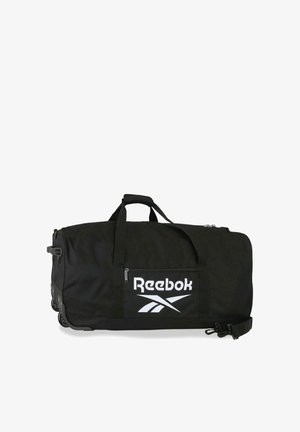 Bolsa de lona con ruedas negra de Reebok con bolsillo con cremallera delantero, asas superiores y correa de hombro desmontable sobre fondo blanco.