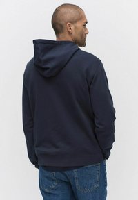 Marinblå hoodie av mjukt material, med en klassisk design och avslappnad passform samt ribbade manschetter och fåll.