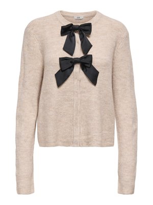 Beige strikket cardigan med rund halsudskæring, med to sorte satin sløjfer fastgjort foran. Lange ærmer og ribbet struktur over det hele.