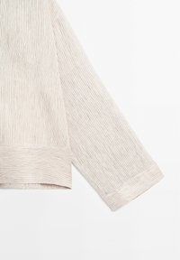 Haut de couleur claire avec des rayures verticales fines, de coupe décontractée et à manches longues. Les poignets sont côtelés, ajoutant de la texture au design.