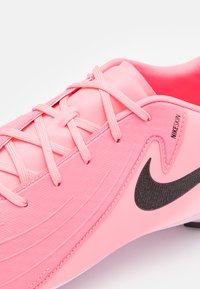 Rózsaszín sportcipő sima textúrával és áramvonalas dizájnnal. Fűzős záródással rendelkezik, valamint egy fekete Nike logóval. Puha anyagból készült.
