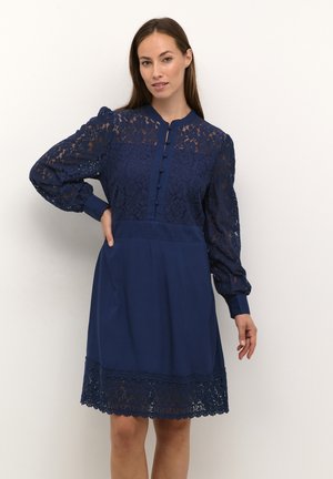 Navy blue dress with a lace bodice, long puff sleeves, and button front. Features floral lace pattern and lace trim at the hem.