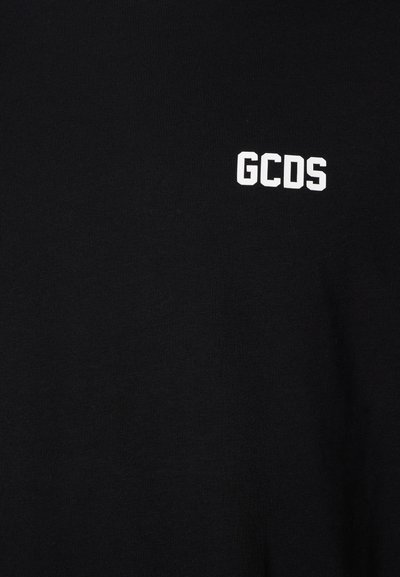 T-shirt preta feita de algodão, com um logotipo branco "GCDS", design minimalista e textura suave.
