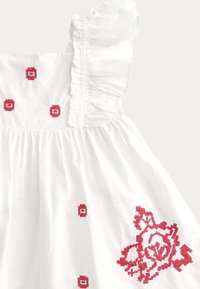Vestido blanco con tirantes con volantes y bordado en punto de cruz rojo de flores y geometría en el corpiño y la falda.