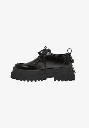 Musta paksupohjainen kiilakorkokenkä, jossa nyöritys ja paksu uritettu pohja sekä kantapään vetokoukkukiinnike, valmistettu kiiltävästä sileästä materiaalista, sivukuva valkoisella taustalla.