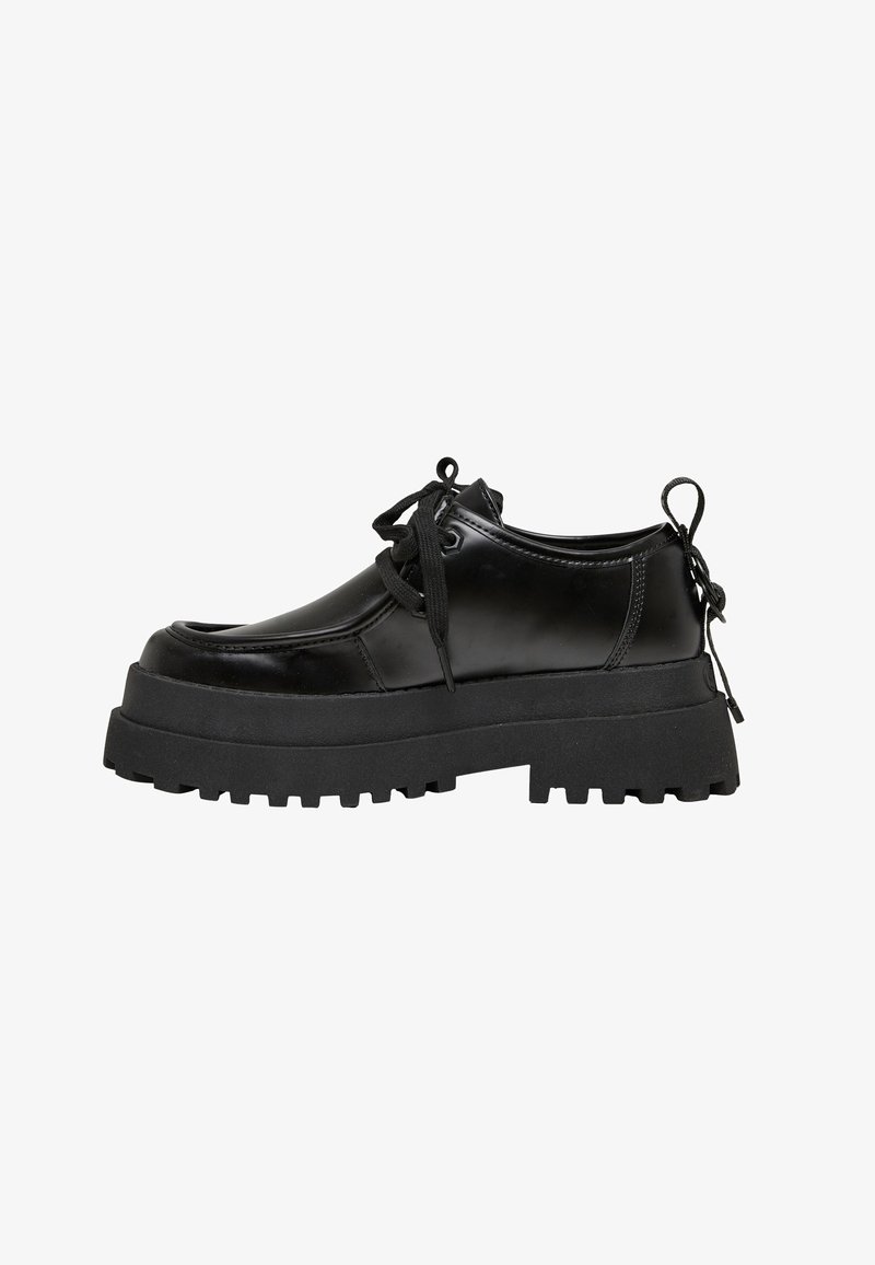 Chaussure plateforme noire épaisse à lacets avec semelle crantée épaisse et languette au talon, fabriquée en matériau lisse et brillant, vue de côté sur fond blanc.