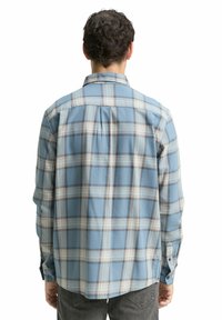 Geruite blouse in lichtblauw met witte en bruine strepen, met lange mouwen en een achterpaneelontwerp. Heeft knopenmanchetten en een gebogen zoom.