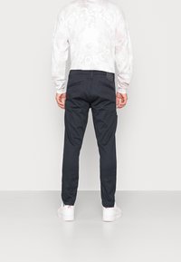 Svarta cargobyxor med sidofickor, med slim fit och en ren design. Materialet verkar vara lätt; passar bra med vita sneakers.