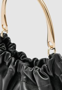 Sort lædertaske med en rynket design, der har et glat guldhåndtag og hardware, der fremhæver teksturen og detaljerne i håndværket.