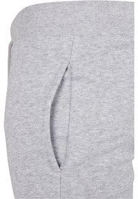 Grå sweatpants gjorda av mjukt tyg, med en ribbad midja och sidofickor. Texturen verkar slät med ett svagt melerat mönster.