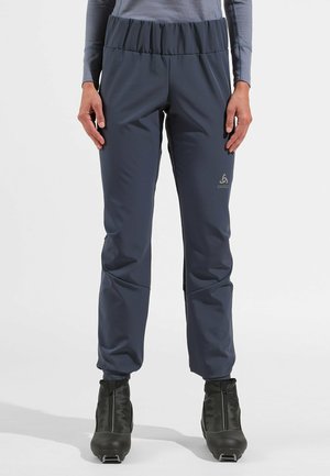 Navy blue, stretch fabric pants with an elastic waistband and tapered leg design, featuring a logo on the left thigh. Suitable for active wear.