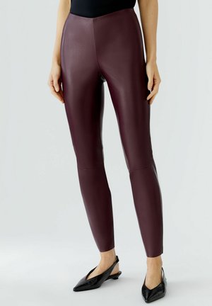 Bordeaux faux leren legging met een gladde textuur, hoge taille en aansluitende pasvorm. Gecombineerd met zwarte puntige ballerina's.