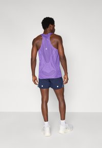 Lila Mesh-Top mit Racerback-Design, kombiniert mit dunkelblauen Shorts mit weißen Akzenten. Weicher Stoff, sportlicher Schnitt für Beweglichkeit.