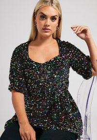 Top negro cubierto de lentejuelas multicolores, con escote cuadrado y mangas cortas, cintura ligeramente ajustada y textura suave.