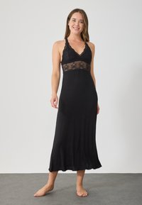 Camisa de noche negra con un corpiño de encaje y un dobladillo fluido. Presenta un diseño de cuello halter y una textura suave y lisa.