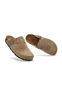 Zuecos de ante marrón claro con detalle de hebilla, que cuentan con una suela de goma negra texturizada y un acabado suave. Adecuados para el uso casual.