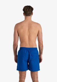 Blauwe zwembroek met een elastische tailleband en een achterzak. Gemaakt van lichte stof met een gladde textuur. Geen patronen of accenten.