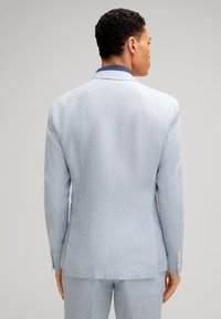 Helles blaues Sakkos mit strukturierter Stoffqualität, einreihigem Design und gebürsteten Silberknöpfen. Verfügt über einen kontrastierenden blauen Kragen.