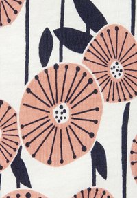 Floral fabric design featuring large pink flowers with black outlines and small white dots on a cream background, interspersed with green leaves.