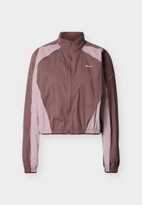 Κοντό, ελαφρύ μπουφάν σε σκούρο μαβί και ανοιχτό ροζ, με ψηλό γιακά, κλείσιμο με φερμουάρ, ελαστικές μανσέτες και διακριτικό λογότυπο στο στήθος.