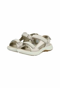 Sandalias de color beige claro fabricadas con material sintético, con tiras de Velcro, punta abierta y suelas acolchadas con una suela blanca texturizada.